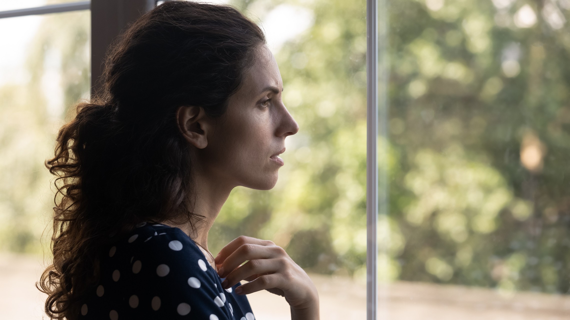 A neighbor in need looks out of the window with concern